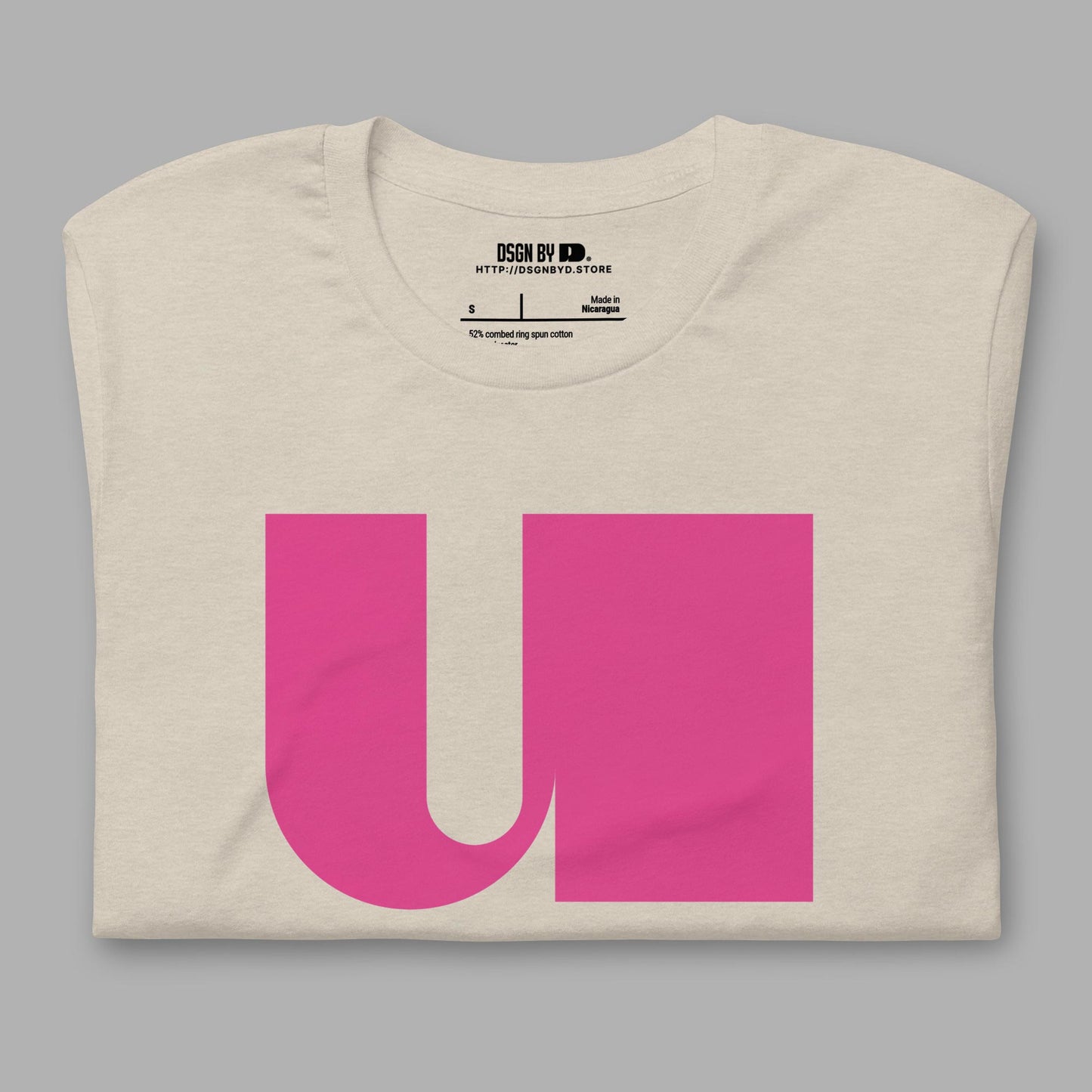 A folded beige cotton unisex graphic tee with letter U.